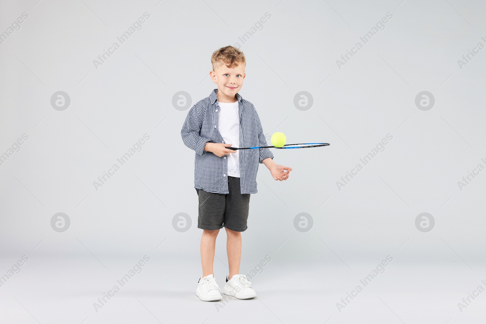 Little boy with racket and tennis ball on gray background Photo of Little boy with racket and tennis ball on gray background