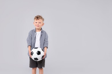 Photo of Little boy with soccer ball on gray background, space for text