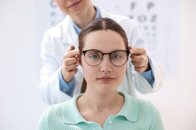 Photo of Ophthalmologist giving glasses to patient in clinic, closeup