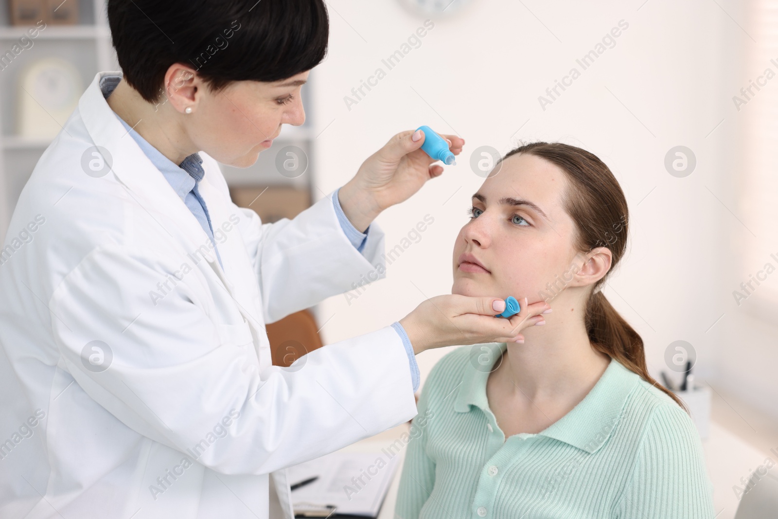 Ophthalmologist applying medical drops onto patient's eye in clinic Photo of Ophthalmologist applying medical drops onto patient's eye in clinic