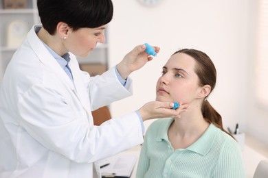 Photo of Ophthalmologist applying medical drops onto patient's eye in clinic