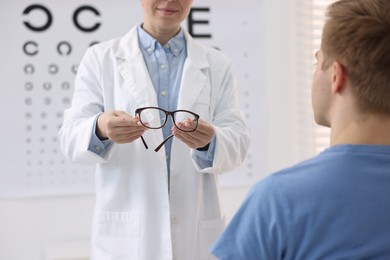 Photo of Ophthalmologist giving glasses to patient in clinic, closeup