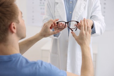 Photo of Ophthalmologist giving glasses to patient in clinic, closeup