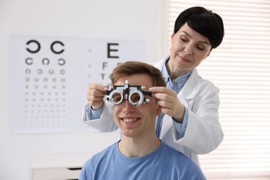 Photo of Ophthalmologist examining patient's vision with trial frame in clinic