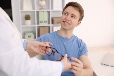 Photo of Ophthalmologist giving glasses to patient in clinic, closeup
