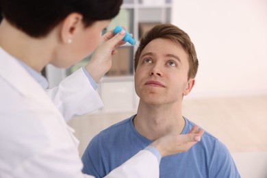 Photo of Ophthalmologist applying medical drops onto patient's eye in clinic, closeup