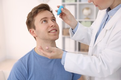 Photo of Ophthalmologist applying medical drops onto patient's eye in clinic, closeup
