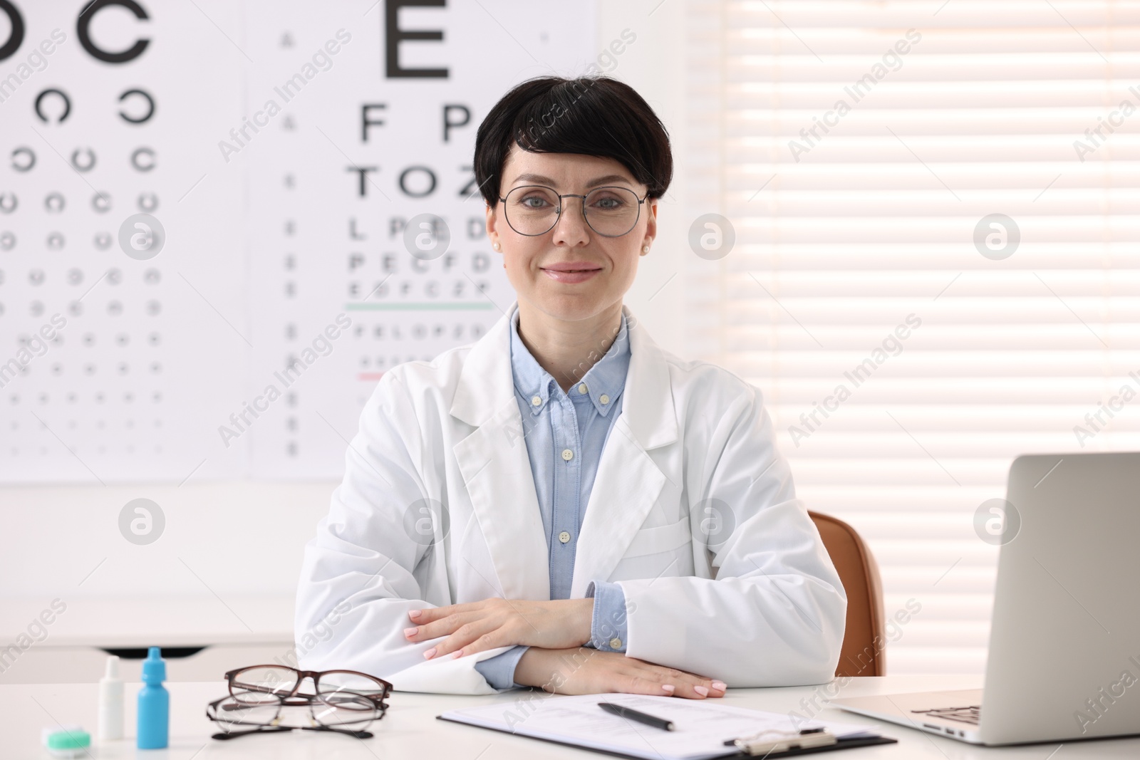 Portrait of professional ophthalmologist at white table in clinic Photo of Portrait of professional ophthalmologist at white table in clinic
