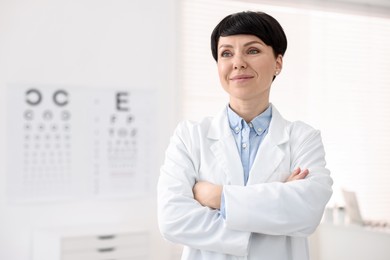 Photo of Portrait of professional ophthalmologist with crossed arms in clinic, space for text