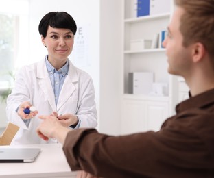 Photo of Ophthalmologist giving contact lenses to patient at white table in clinic
