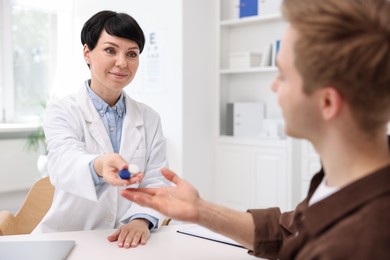 Photo of Ophthalmologist giving contact lenses to patient at white table in clinic