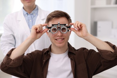 Photo of Ophthalmologist examining patient's vision with trial frame in clinic, closeup