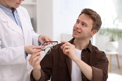 Photo of Ophthalmologist giving glasses to patient in clinic, closeup