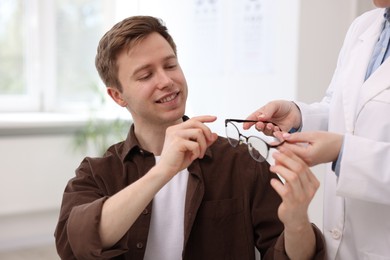 Photo of Ophthalmologist giving glasses to patient in clinic, closeup