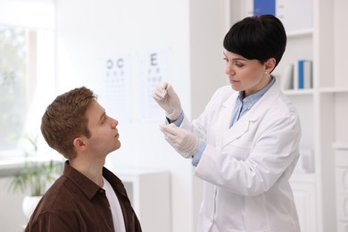 Photo of Professional ophthalmologist teaching patient to use contact lenses in clinic