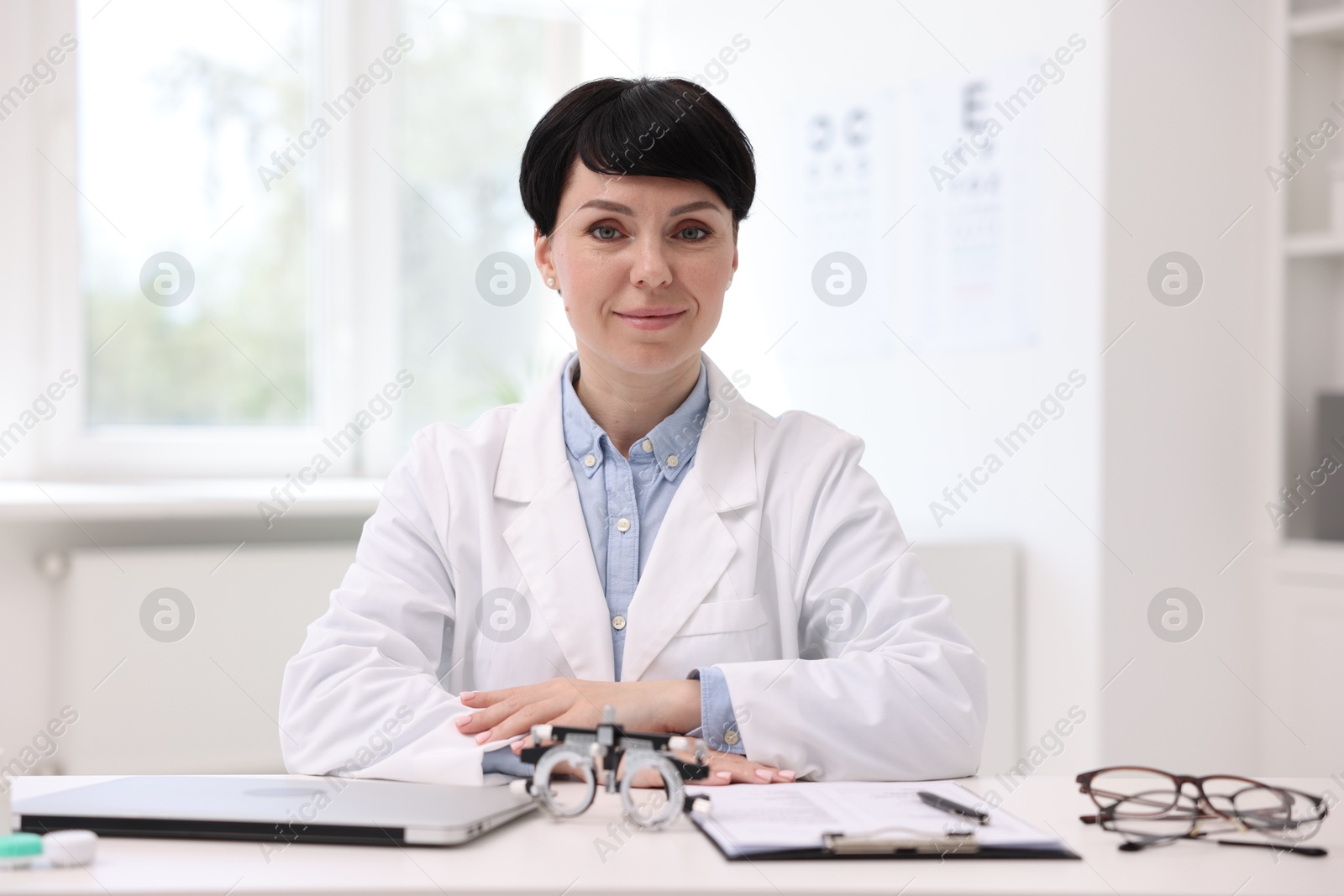Portrait of professional ophthalmologist at white table in clinic Photo of Portrait of professional ophthalmologist at white table in clinic