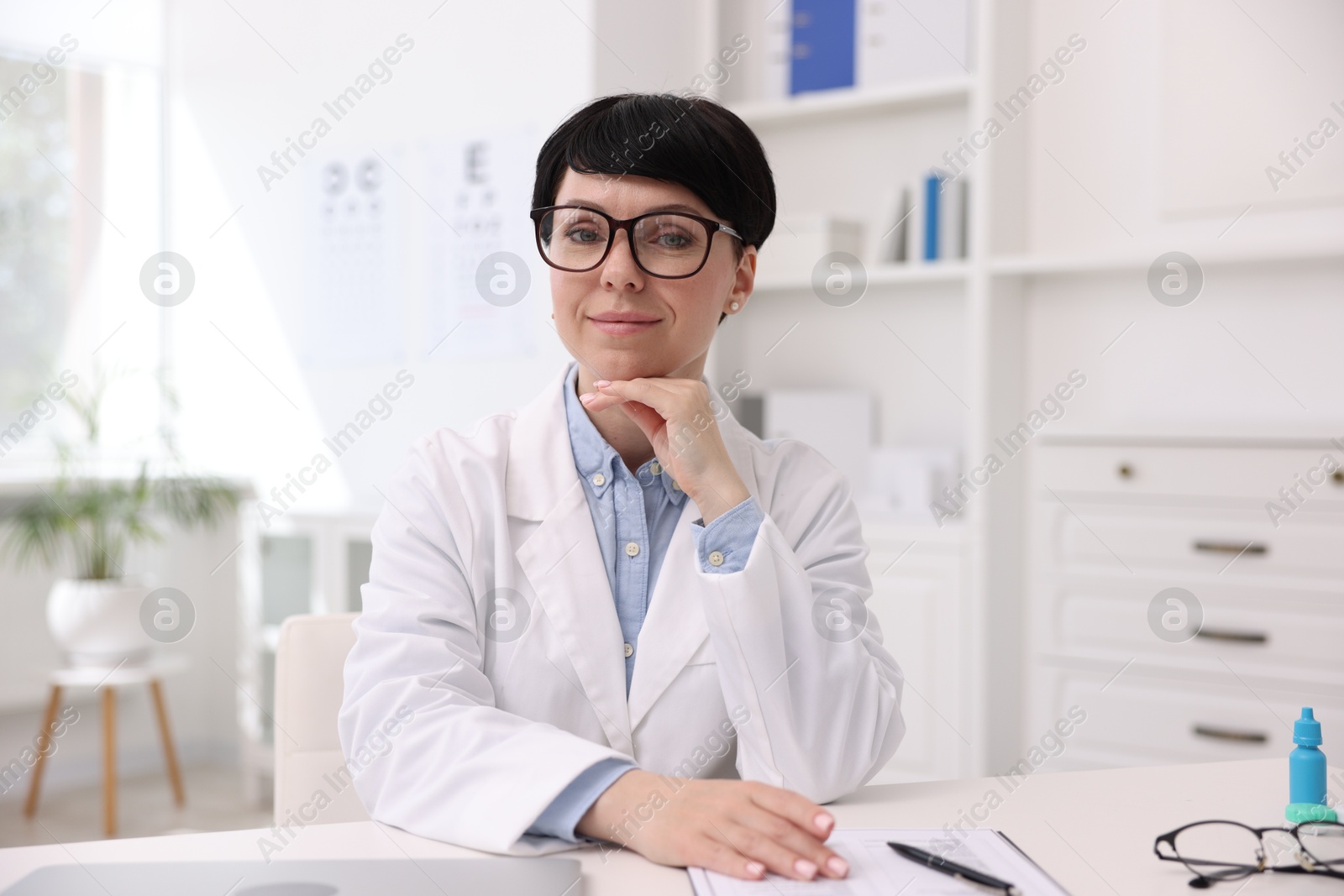 Portrait of professional ophthalmologist at white table in clinic Photo of Portrait of professional ophthalmologist at white table in clinic