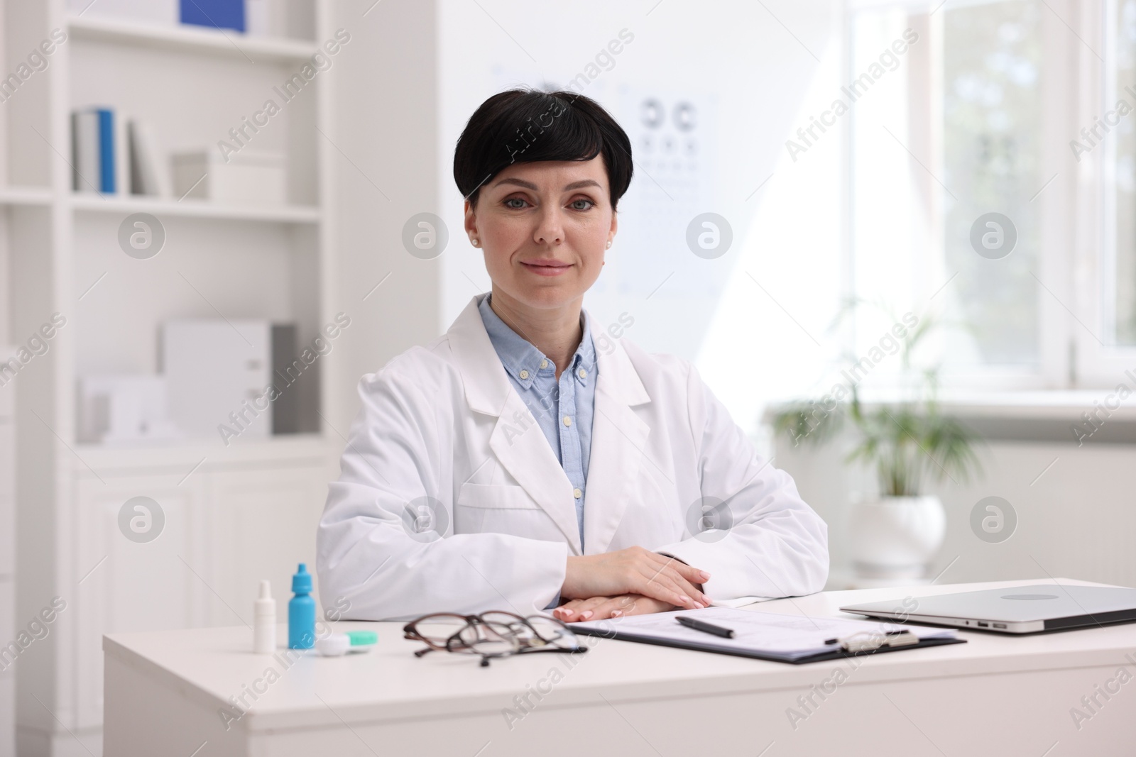 Portrait of professional ophthalmologist at white table in clinic Photo of Portrait of professional ophthalmologist at white table in clinic