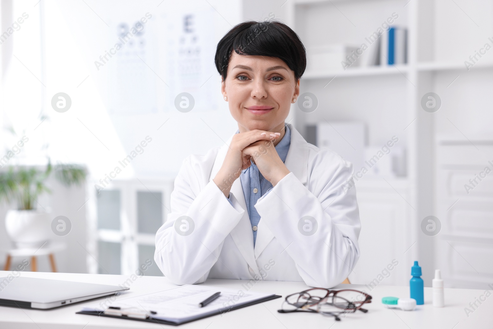 Portrait of professional ophthalmologist at white table in clinic Photo of Portrait of professional ophthalmologist at white table in clinic