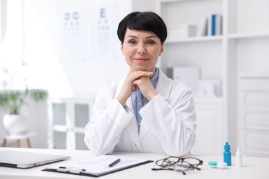 Photo of Portrait of professional ophthalmologist at white table in clinic
