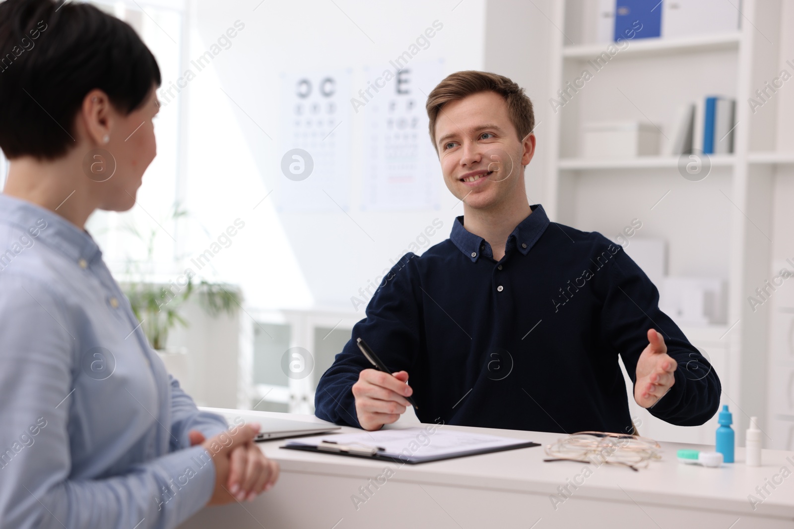 Ophthalmologist consulting woman at white table in clinic Photo of Ophthalmologist consulting woman at white table in clinic