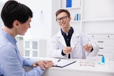 Photo of Ophthalmologist consulting woman at white table in clinic