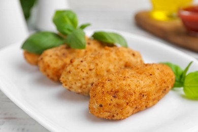Photo of Tasty fried croquettes and basil on white wooden table, closeup