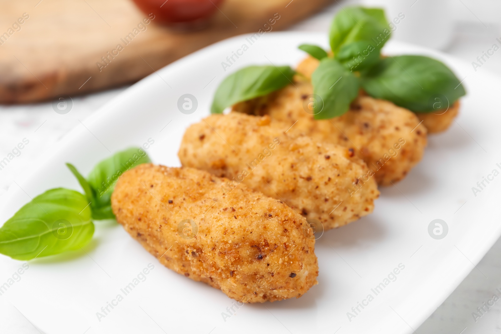 Tasty fried croquettes and basil on white wooden table, closeup Photo of Tasty fried croquettes and basil on white wooden table, closeup