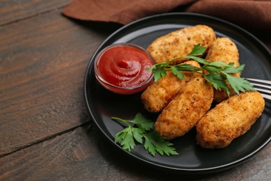 Photo of Tasty fried croquettes, parsley and sauce on wooden table, closeup. Space for text