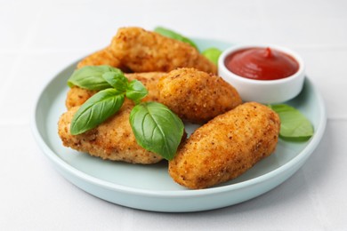 Photo of Tasty fried croquettes, basil and sauce on white tiled table, closeup
