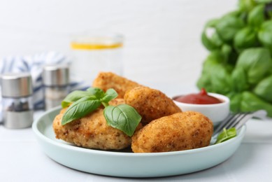Photo of Tasty fried croquettes, basil and sauce on white tiled table, closeup