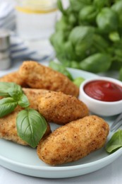 Photo of Tasty fried croquettes, basil and sauce on white tiled table, closeup