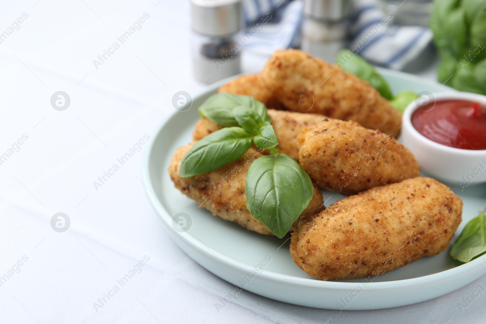 Tasty fried croquettes, basil and sauce on white tiled table, closeup. Space for text Photo of Tasty fried croquettes, basil and sauce on white tiled table, closeup. Space for text