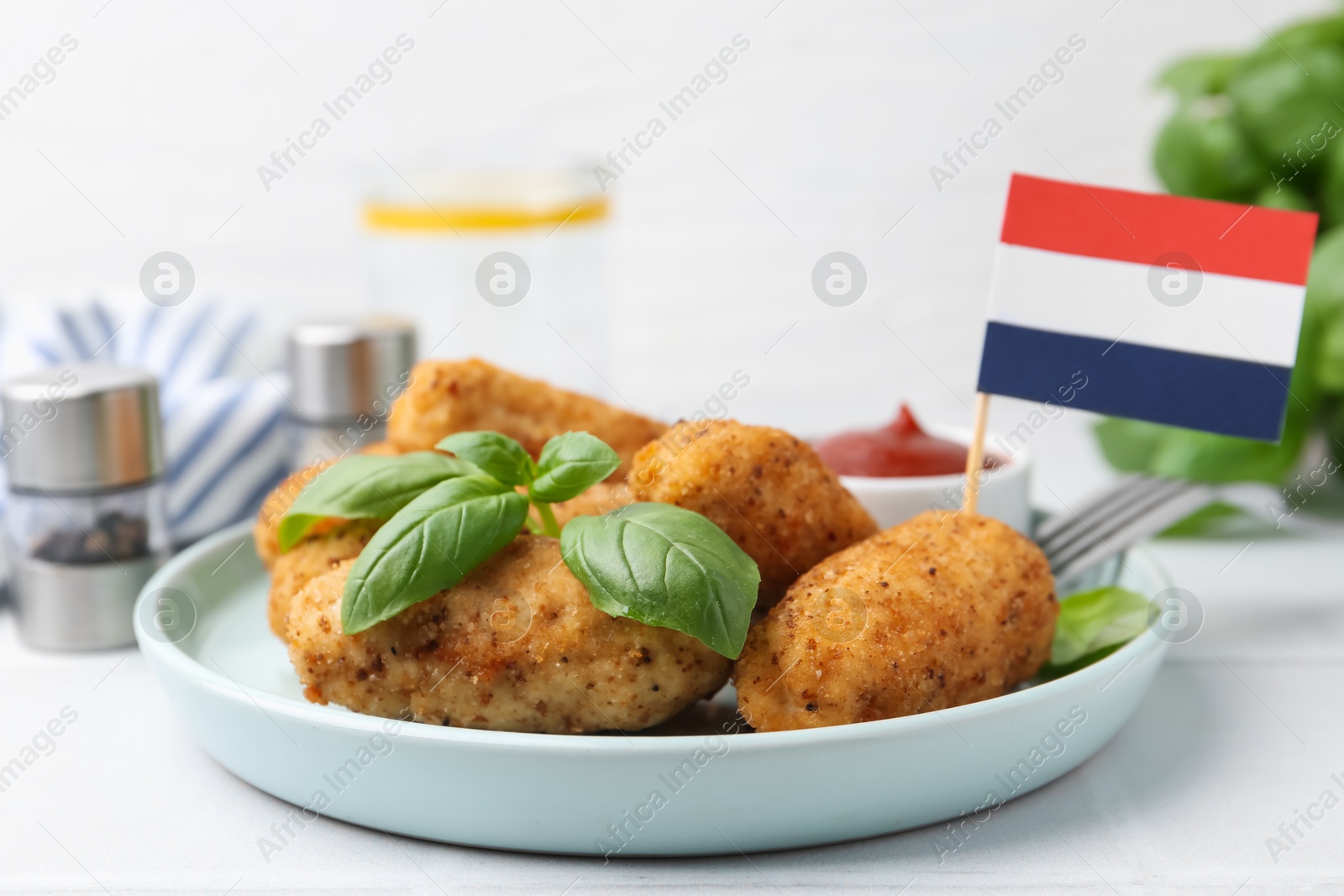 Tasty fried croquettes, basil, sauce and flag of Netherlands on white tiled table, closeup Photo of Tasty fried croquettes, basil, sauce and flag of Netherlands on white tiled table, closeup