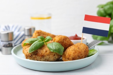 Photo of Tasty fried croquettes, basil, sauce and flag of Netherlands on white tiled table, closeup