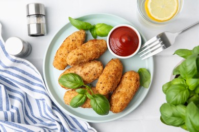Photo of Tasty fried croquettes, basil and sauce served on white tiled table, flat lay