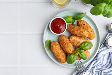 Photo of Tasty fried croquettes, basil and sauce on white tiled table, flat lay. Space for text