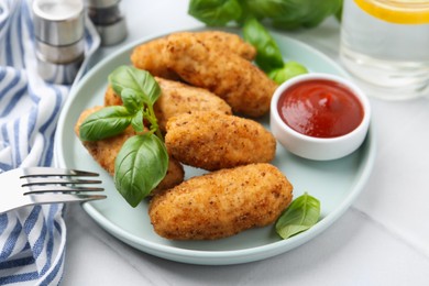 Photo of Tasty fried croquettes, basil and sauce on white tiled table, closeup