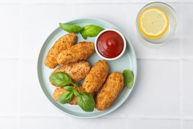Photo of Tasty fried croquettes, basil and sauce served on white tiled table, top view