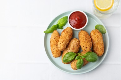 Photo of Tasty fried croquettes, basil and sauce served on white tiled table, top view. Space for text