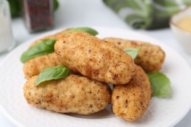 Photo of Tasty fried croquettes and basil on white table, closeup