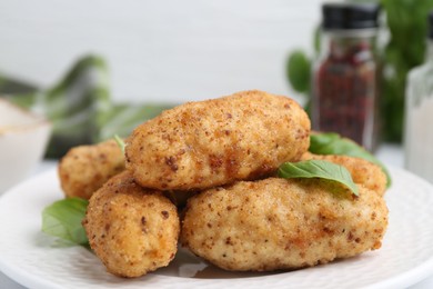 Photo of Tasty fried croquettes and basil on table, closeup