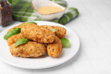 Photo of Tasty fried croquettes, basil and sauce on white tiled table, closeup. Space for text