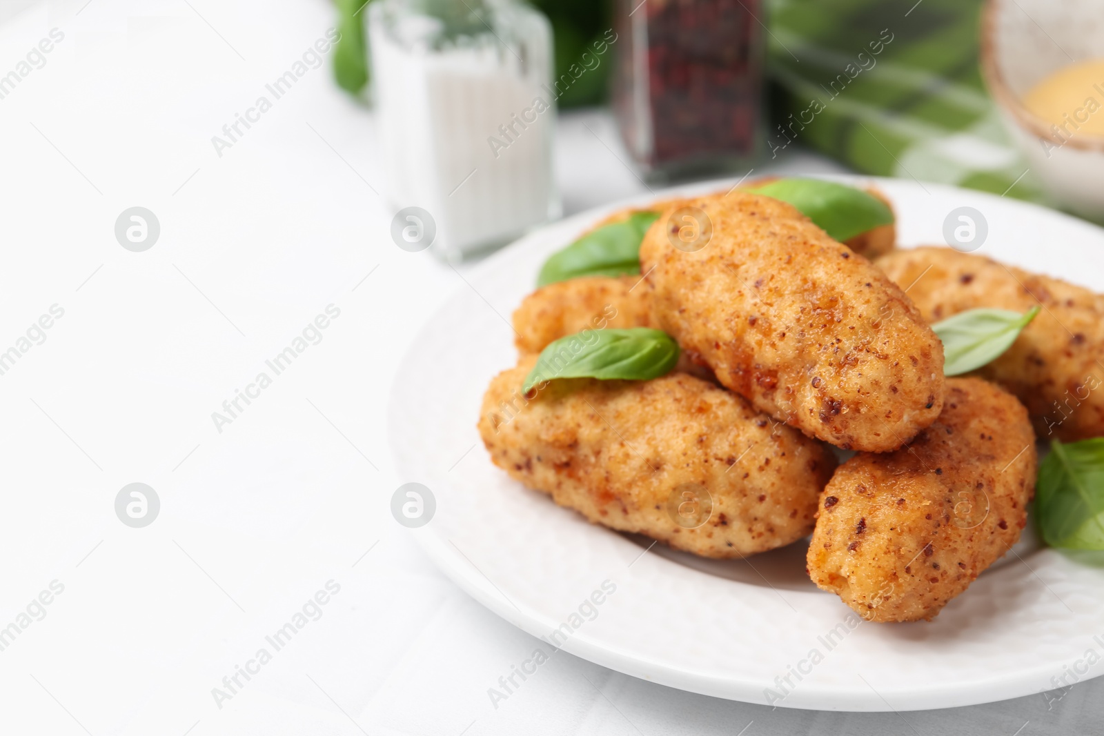 Tasty fried croquettes, basil and sauce on white tiled table, closeup. Space for text Photo of Tasty fried croquettes, basil and sauce on white tiled table, closeup. Space for text