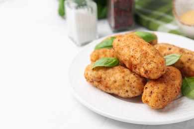 Photo of Tasty fried croquettes, basil and sauce on white tiled table, closeup. Space for text