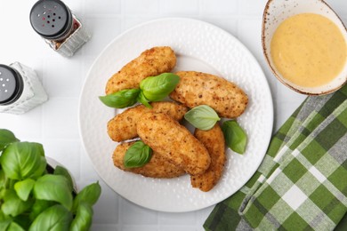 Photo of Tasty fried croquettes, basil and sauce on white tiled table, flat lay