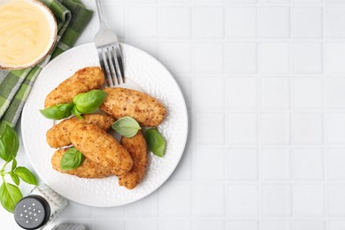 Photo of Tasty fried croquettes, basil and sauce on white tiled table, flat lay. Space for text