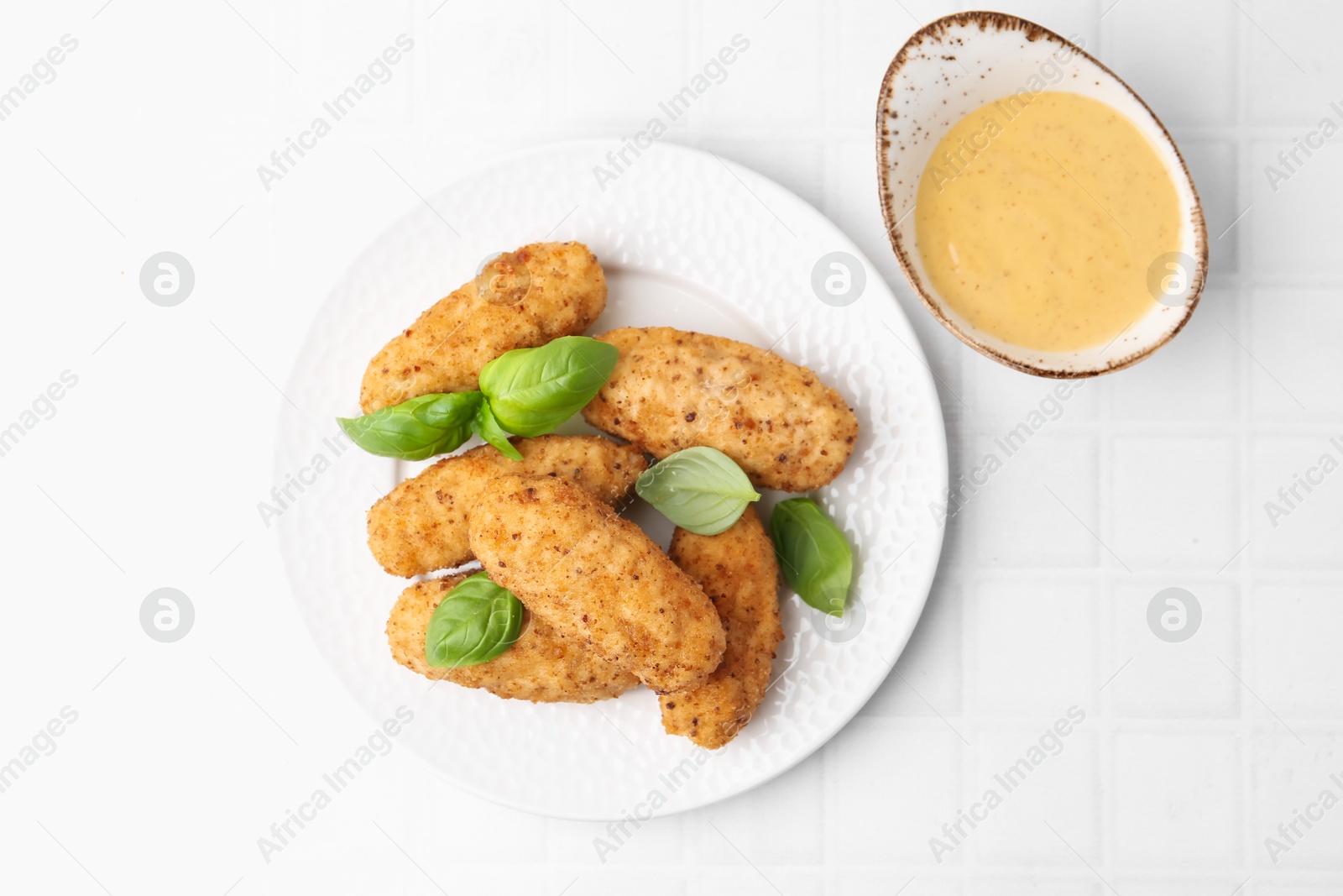Tasty fried croquettes, basil and sauce on white tiled table, top view Photo of Tasty fried croquettes, basil and sauce on white tiled table, top view
