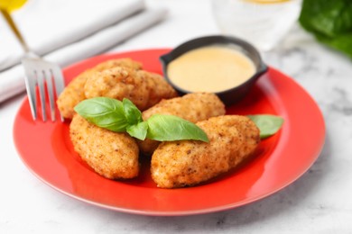 Photo of Tasty fried croquettes, basil and sauce on white marble table, closeup