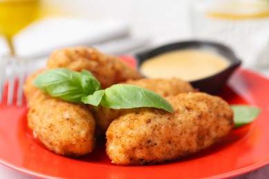 Photo of Tasty fried croquettes, basil and sauce on table, closeup